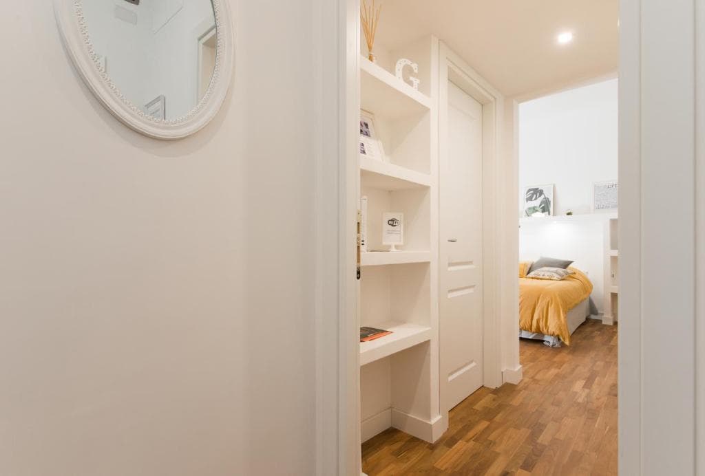 Hallway with round mirror, built-in bookshelf and view into the bedroom